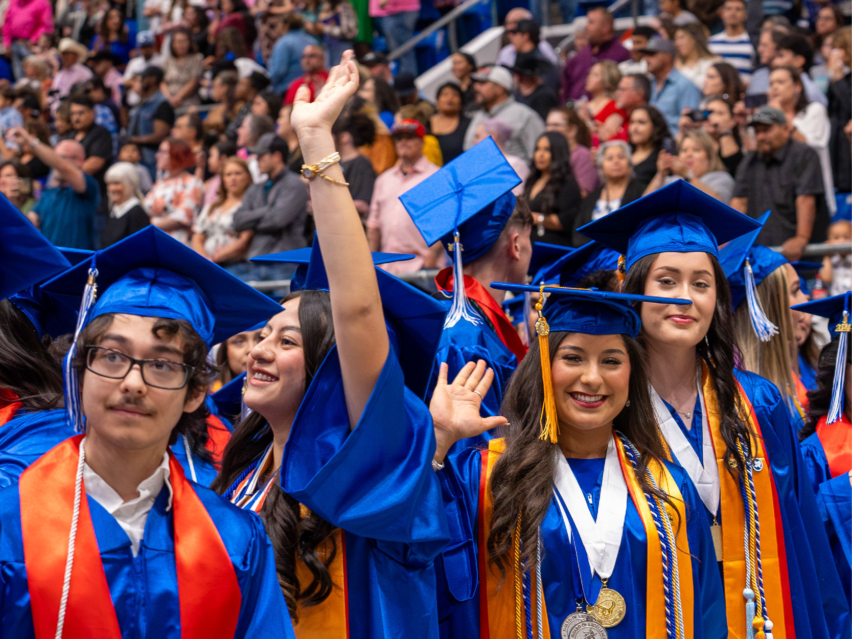 Graduates in Blue Caps and Gowns Waving and Smiling