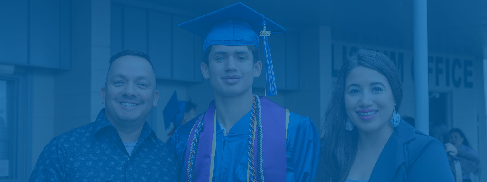 Student in Blue Cap and Gown Posing with Family After Graduation Ceremony