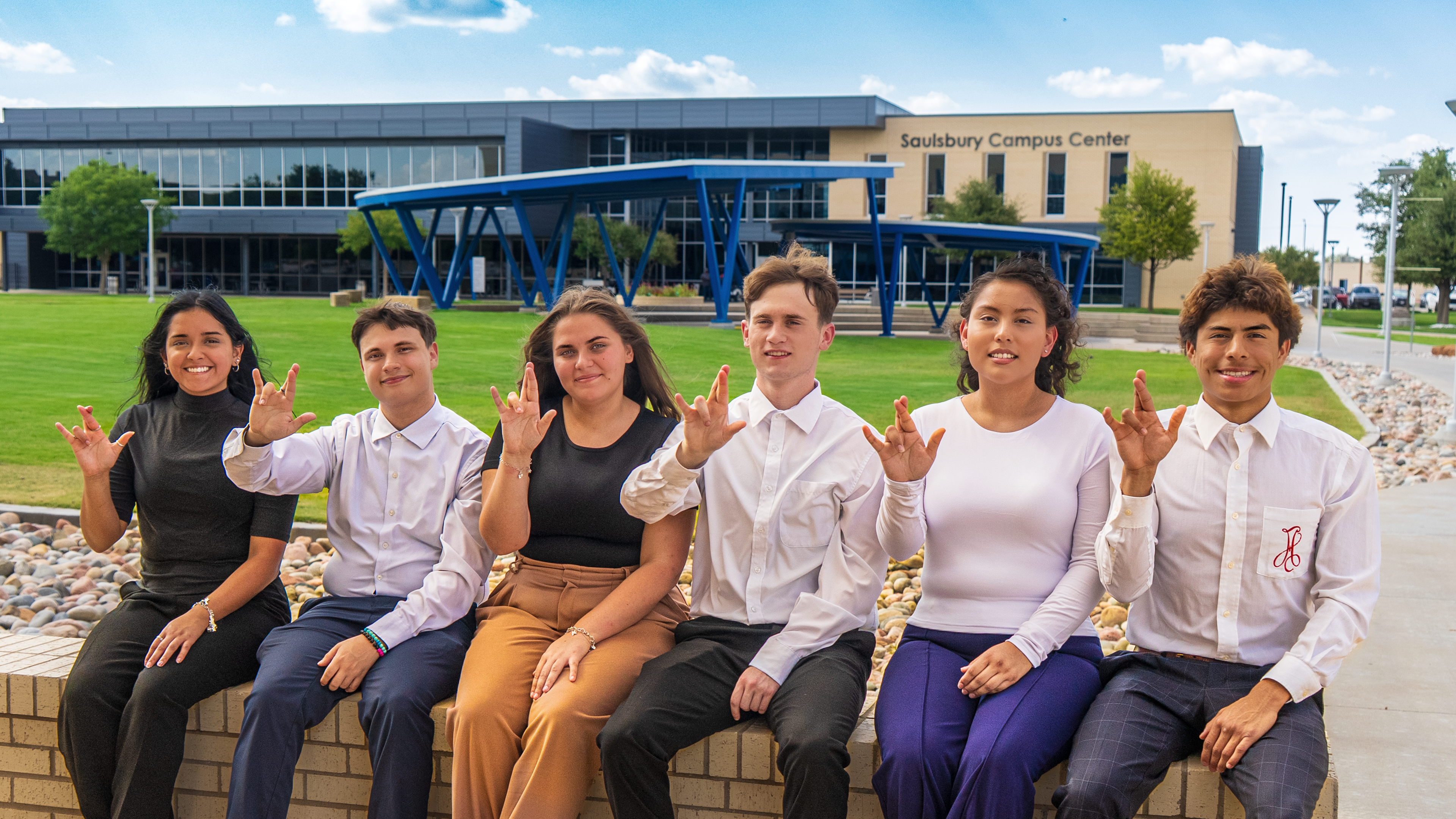 Students sitting down and doing the wrangler sign with their hands