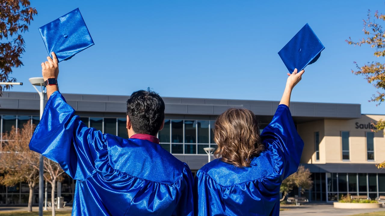 Sendra and Cesar Rios with their back to the camera as they raise their caps