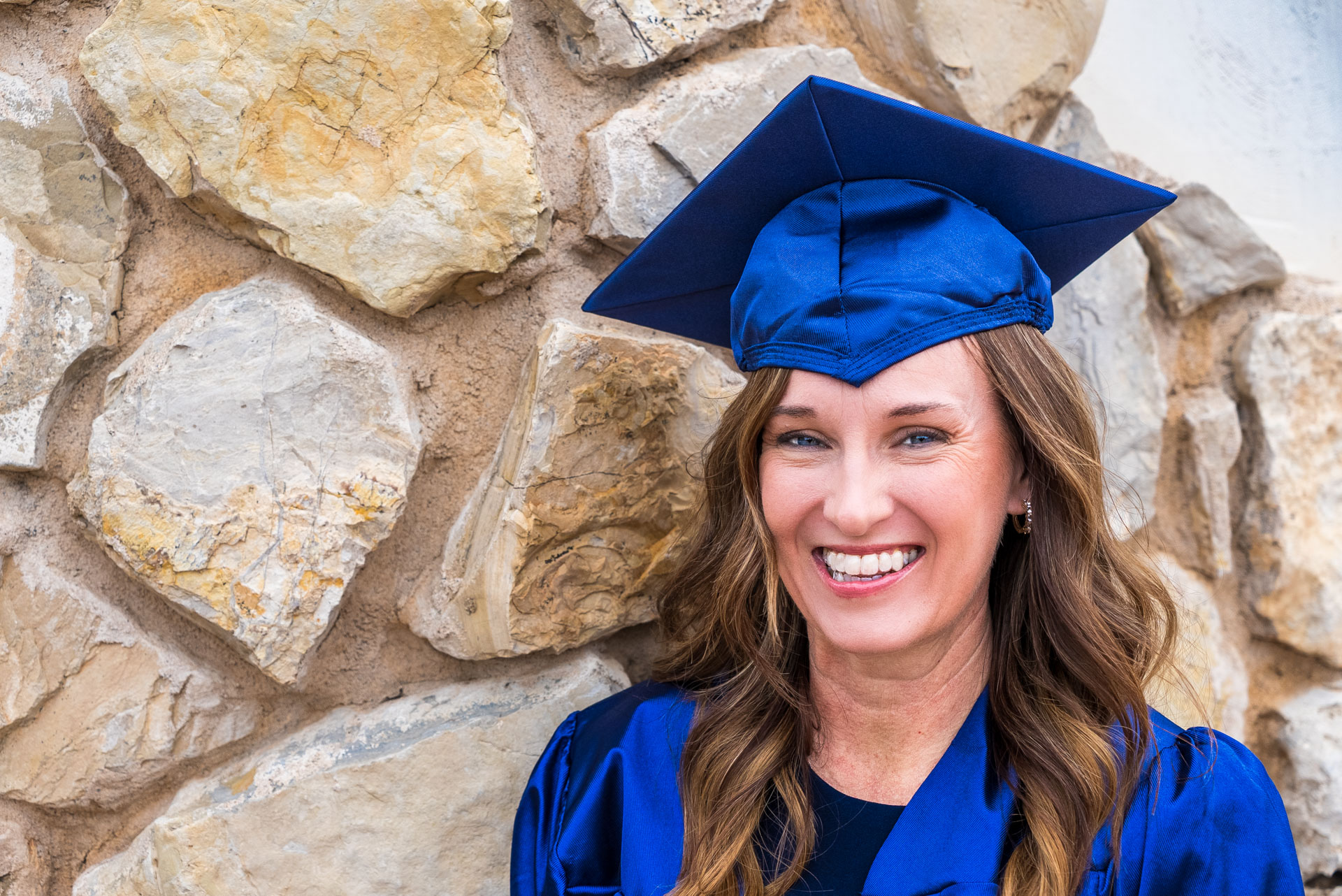 Candy Duke smiling in front of stone wall