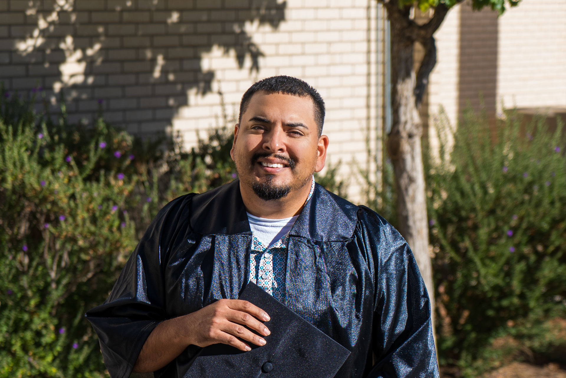 Luis Sigala smiling in front of building with plants