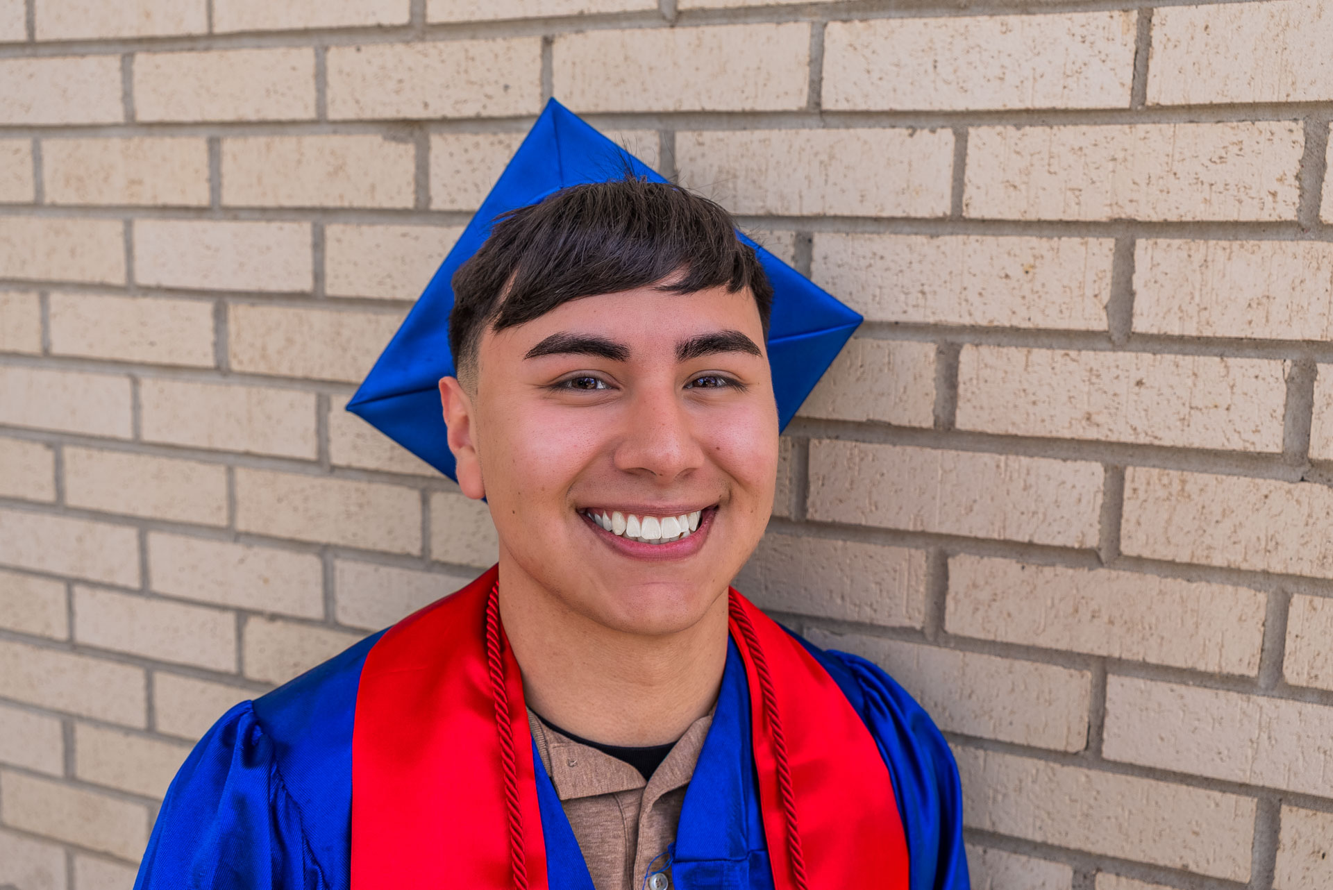 Raul Barrera smiling in front of brick wall