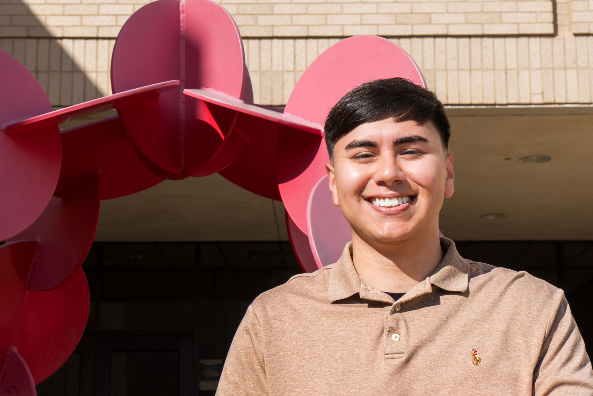 Raul Barrera smiling in front of red sculpture